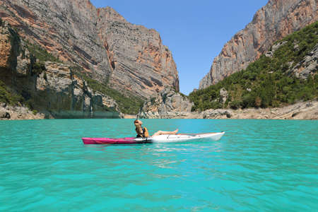Side view portrait of a woman relaxing on kayak resting in a lake on summer vacationの写真素材