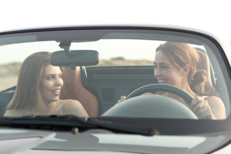 Two happy friends talking in a convertible carの写真素材