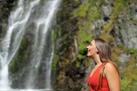 Side view portrait of an amazed woman contemplating waterfallの写真素材
