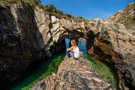 Happy trekker sitting on a rock contemplating views in a paradise beachの写真素材