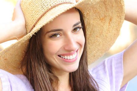 Happy woman wearing pamela and perfect smile looking at you outdoorsの写真素材