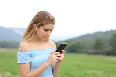 Concentrated teen in a field using smart phoneの写真素材