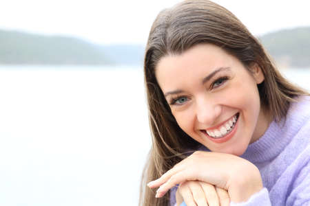 Beautiful teen smiling at camera sitting in a lakeの写真素材