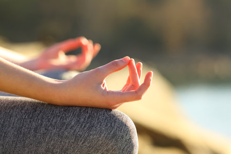 Close up of a woman hands doing yoga exercise in a lakeの写真素材