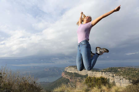Excited woman jumping celebrating holiday in natureの写真素材