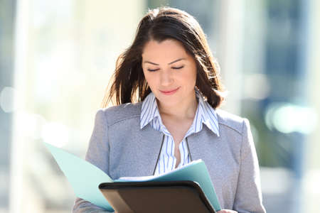 Front view of a businesswoman reading report walking in the streetの写真素材