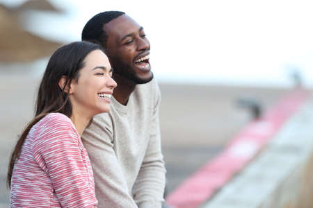 Happy interracial couple laughing dating in a pierの写真素材