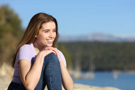Happy woman contemplating views sitting in a beautiful lakeの写真素材