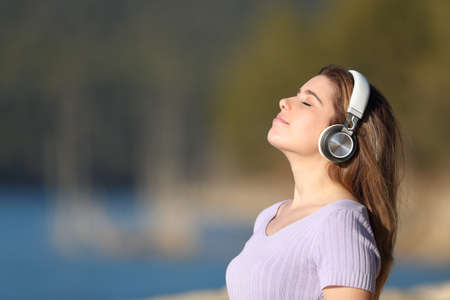 Profile of a young woman meditating with wireless headphones in a lakeの写真素材