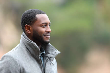 Satisfied man with black skin contemplating looking at side outdoorsの写真素材