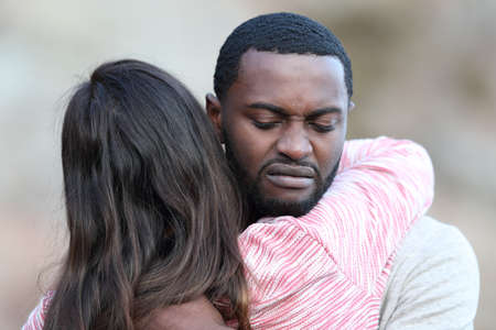 Disgusted man with black skin hugging and rejecting to a caucasian woman outdoorsの写真素材