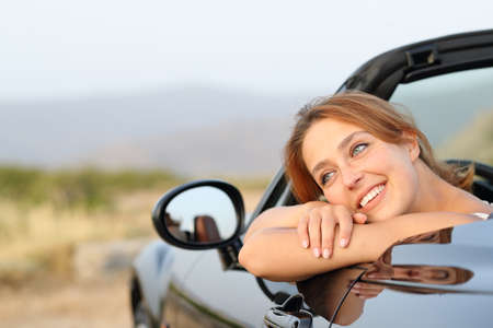 Happy owner resting sitting in a convertible car looking away in the roadsideの写真素材