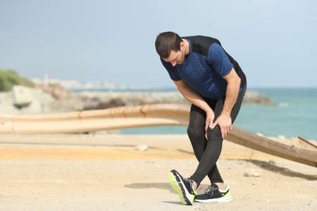 Runner stretching leg after sport on the beachの写真素材