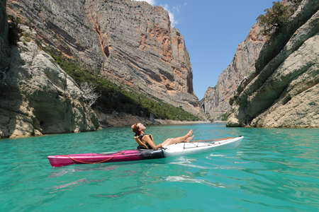 Relaxed woman on kayak resting and breathing fresh air in a lake on summer vacationの写真素材