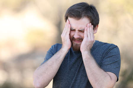 Stressed man suffering migraine attack outdoorsの写真素材
