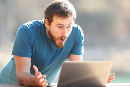 Amazed man checking laptop content outdoors a sunny dayの写真素材