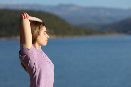 Side view portrait of a concentrated woman stretching arms in nature after sport