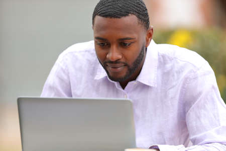 Handsome man with black skin using laptop in a coffee shop terraceの写真素材