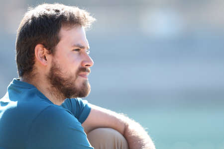 Profile of a pensive relaxed man contemplating views sitting in a lakeの写真素材