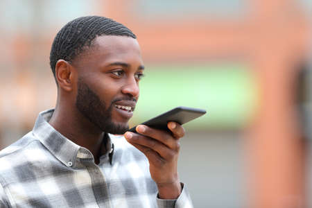 Man with black skin using voice recognition on cellphone in the streetの写真素材