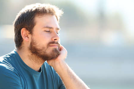 Relaxed man resting outdoors with closed eyes on a sunny dayの写真素材