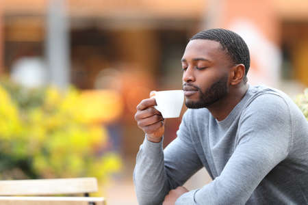 Man with black skin relaxing drinking coffee in a bar terraceの写真素材