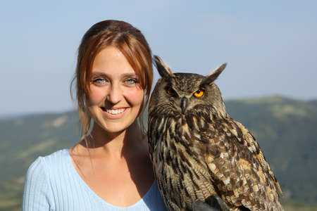 Front view portrait of a happy falconer with an eagle owl looking at cameraの写真素材