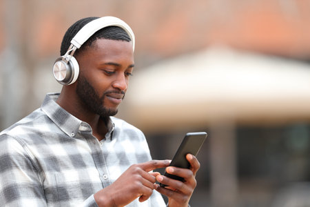 Man with black skin wearing headphones listening to music walks in the streetの写真素材