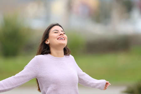 Happy teen outstretching arms breathing and celebrating in a parkの写真素材