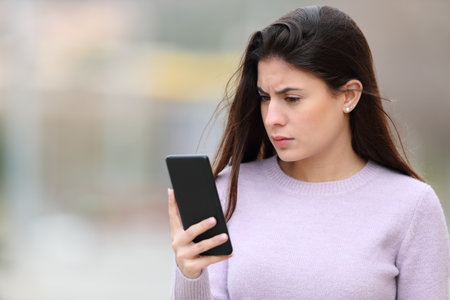 Worried woman reading smart phone content in the streetの写真素材