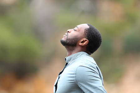 Side view portrait of a man with black skin breaths fresh air outsideの写真素材