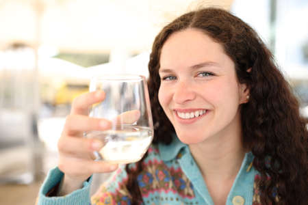 Happy woman holding water glass looks at you in a bar terraceの写真素材