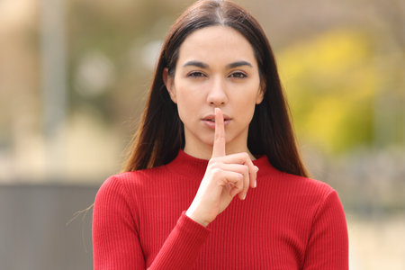 Front view portrait of a serious woman in red asking for silence in the streetの写真素材