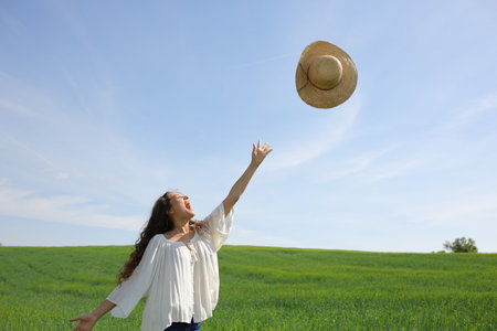 Happy woman throwing pamela hat to the air in a wheat fieldの写真素材