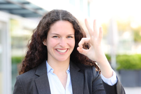 Front view portrait of a happy executive gesturing ok in the streetの写真素材