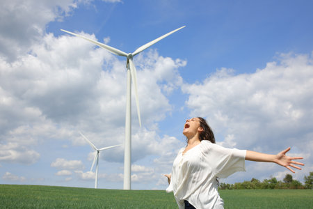 Happy woman outstretching arms screaming to the air celebrating in a wind farmの写真素材