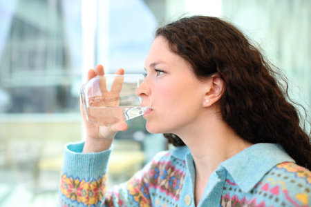 Side view portrait of a woman drinking water from glass in a bar terraceの写真素材