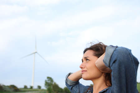 Annoyed woman covering ears with hands suffering windmill noise in a wind farm