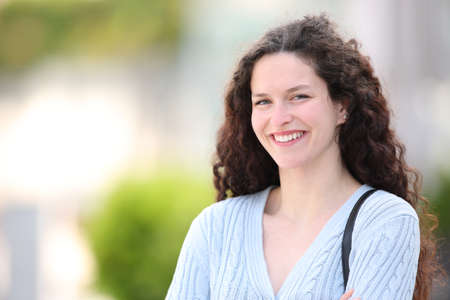 Portrait of a happy woman with curly hair standing in the streetの写真素材