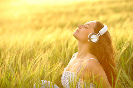 Profile of a relaxed woman meditating listening to music at sunset in a fieldの写真素材