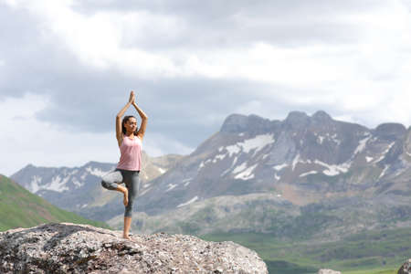 Full body portrait of a yogi practicing yoga exercise on the top of a high mountainの写真素材