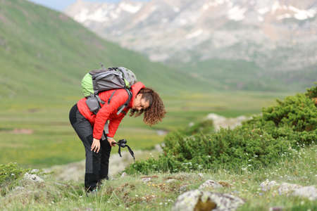 Exhausted hiker in red resting in a high mountain field after climbing
