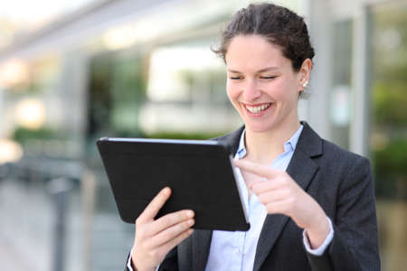 Happy executive using digital tablet walking in the streetの写真素材
