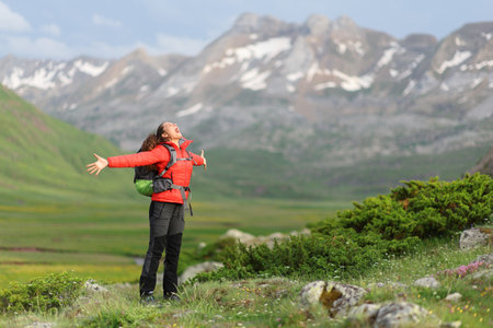 Excited hiker celebrating vacation outstretching arms and screaming in a high mountainの写真素材