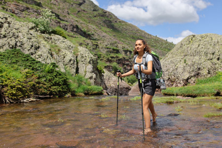 Happy barefoot hiker crossing river in the mountainの写真素材