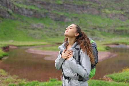 Relaxed hiker breathing fresh air with hands on chest in natureの写真素材