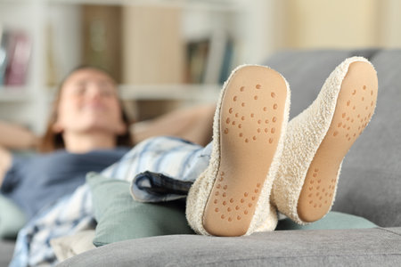 Happy woman wearing slippers resting lying on a couch at homeの写真素材