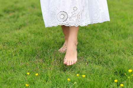 Front view portrait of a woman bare feet walking on the grassの写真素材