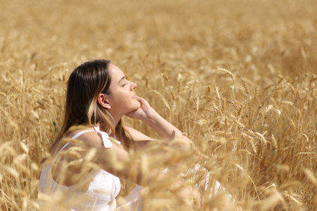 Profile of a relaxed woman resting in a golden wheat fieldの写真素材