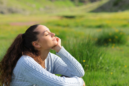 Casual woman relaxing sitting in a green field on the mountainの写真素材